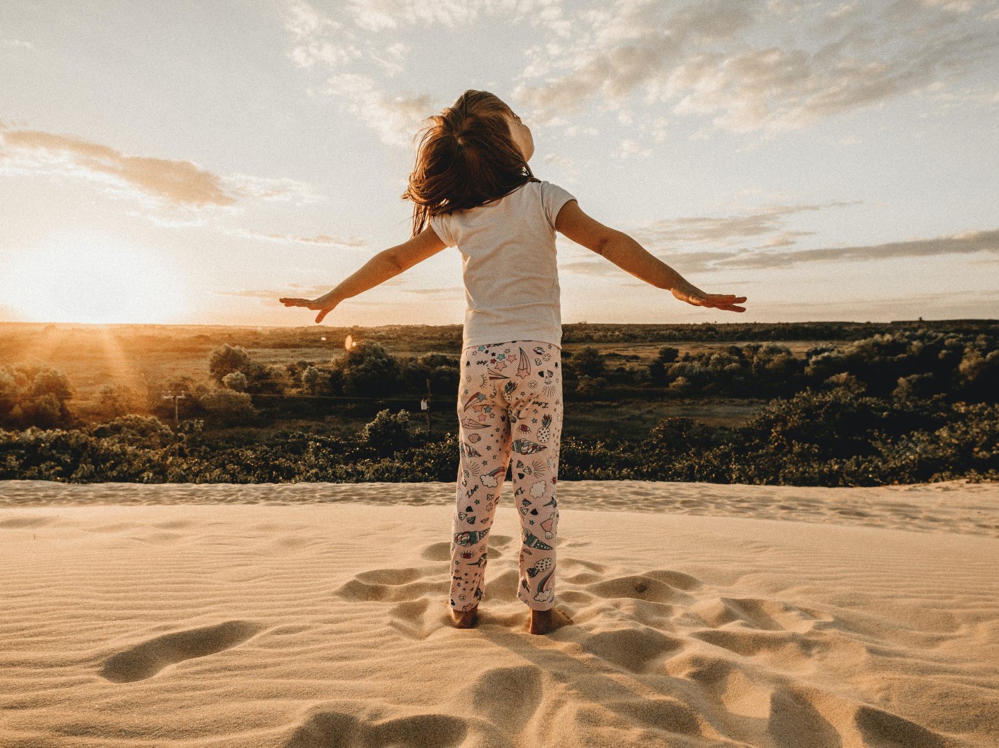Cover picture of the article: Children's Day Activities - Algarve. In the photo, a child looks up to the sky with open arms while standing on a dune.